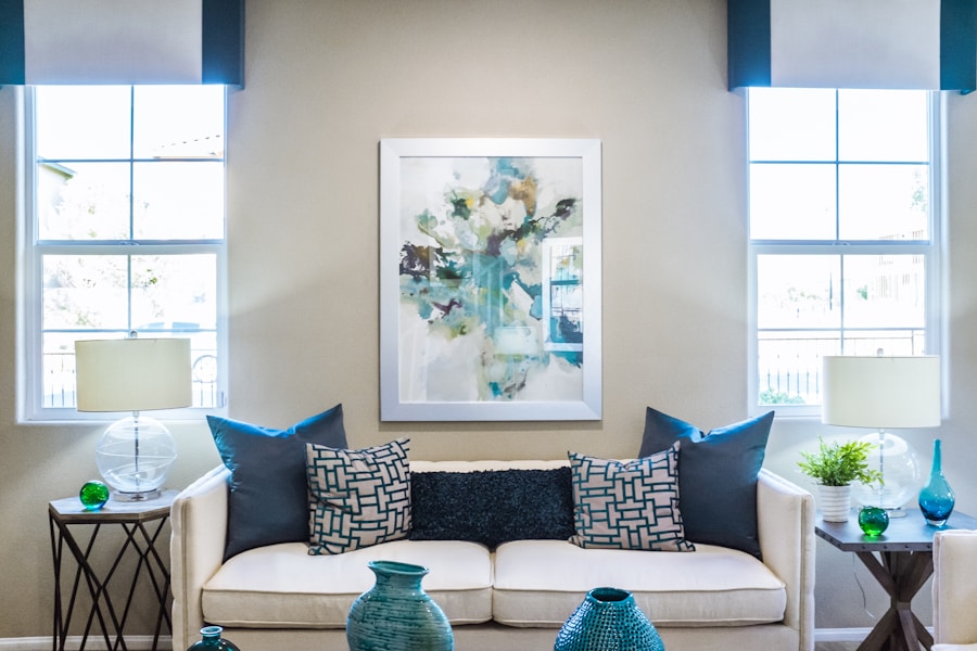 Helles Wohnzimmer mit weißem Sofa, abstraktem Wandbild und türkisfarbenen Kissen, davor mehrere blaue Vasen