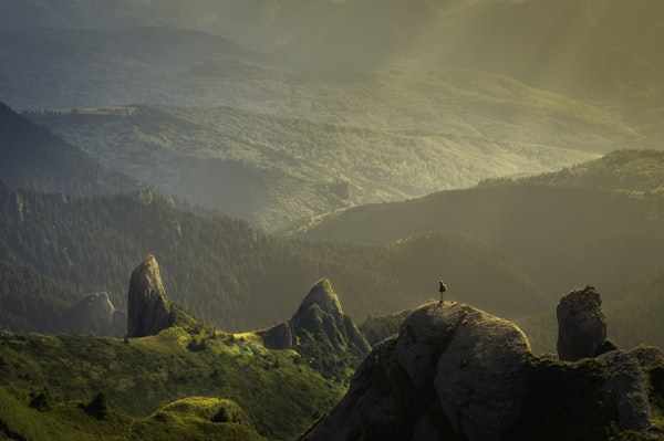 Sanfte Berglandschaft mit grünen Hügeln und Felsspitzen im Abendlicht